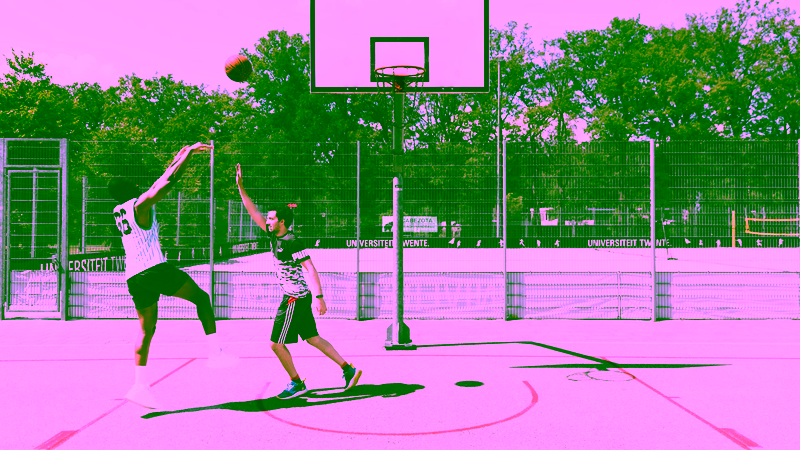 Two students playing basketball on campus.