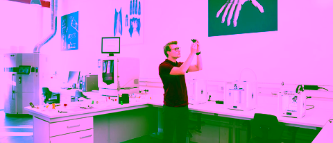 A student inspecting a 3D-printed prototype in an industrial design laboratory