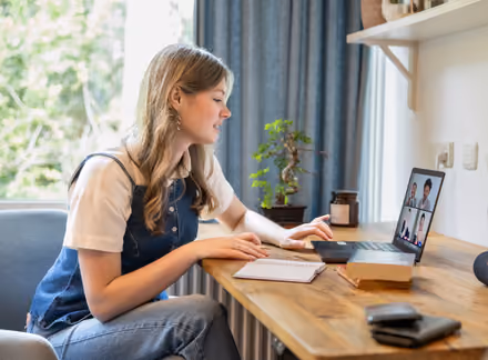 Girl sitting at a desk in her room attending an Online Open Day of the University of Twente