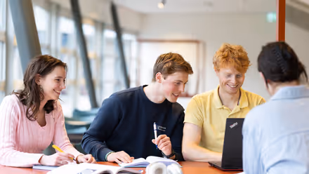 Four students sit at the table and talk