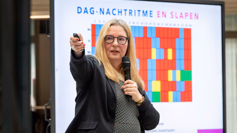 Researcher giving a presentation on sleep and circadian rhythm, pointing at a screen showing a colourful chart with the title