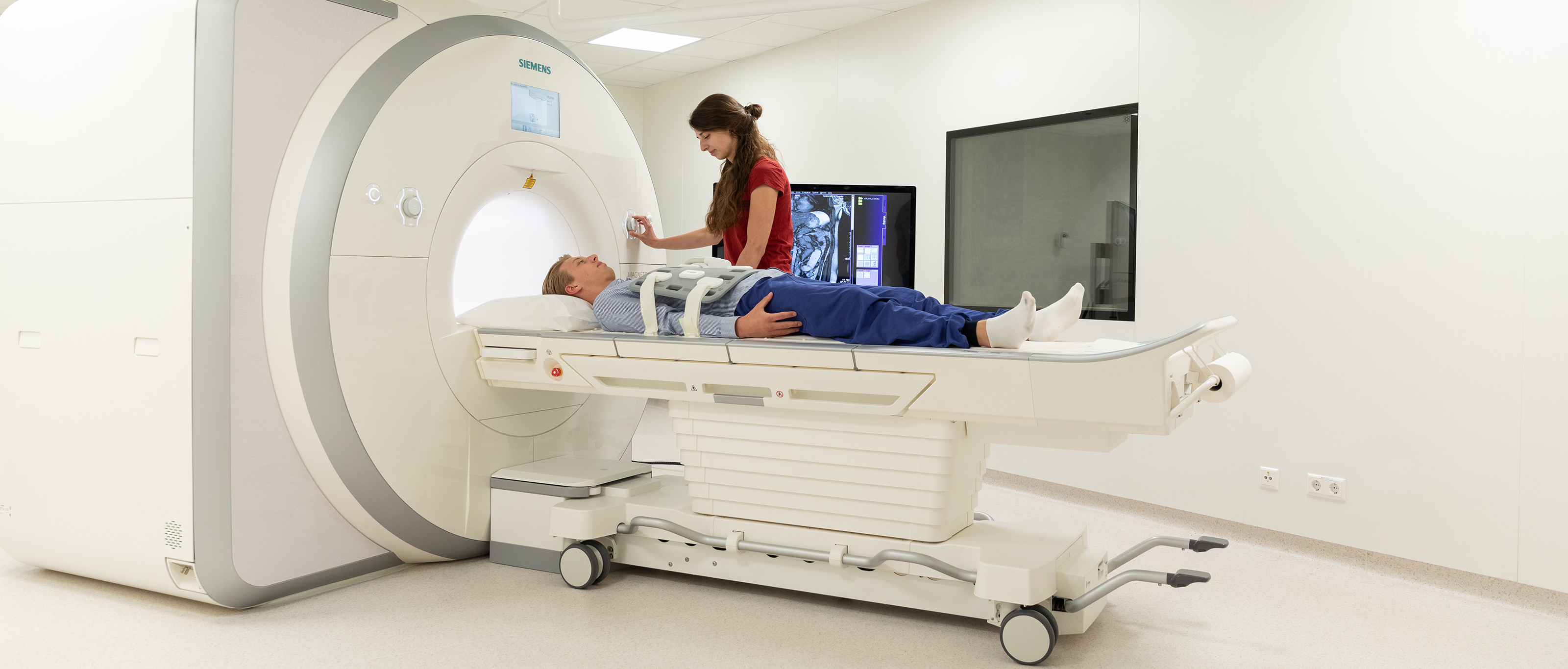 Student operates an MRI scanner while a patient lies on the table, ready for a scan.
