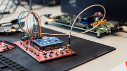 Workspace featuring electronic circuit boards interconnected with colorful wires in a close-up view.