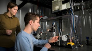 Students are working on a setup with precision equipment and measuring instruments in a laboratory.