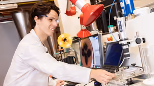 Lab work with microscopic imaging and instruments, illustrating material analysis and flow behavior in energy systems.