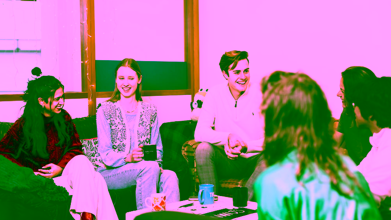 A group of six students sitting in a study association room talking.