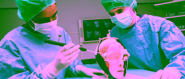 Twee mensen in een laboratoriumjas tijdens een chirurgische training met een anatomisch hoofdmodel in een klinische omgeving.
