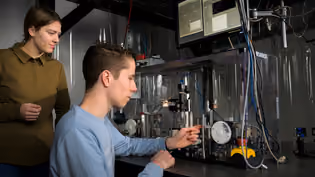 Students are working on a setup with precision equipment and measuring instruments in a laboratory.