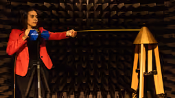 An Electrical Engineering student stands in an anechoic chamber, testing her project work.