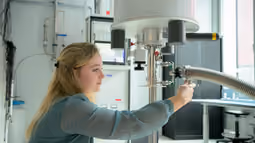 Student is adjusting a setup and taking measurements in a laboratory for quantum research.