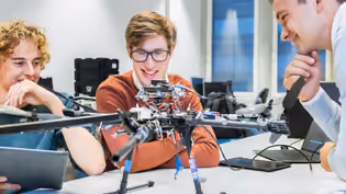 Robotics students looking at drone