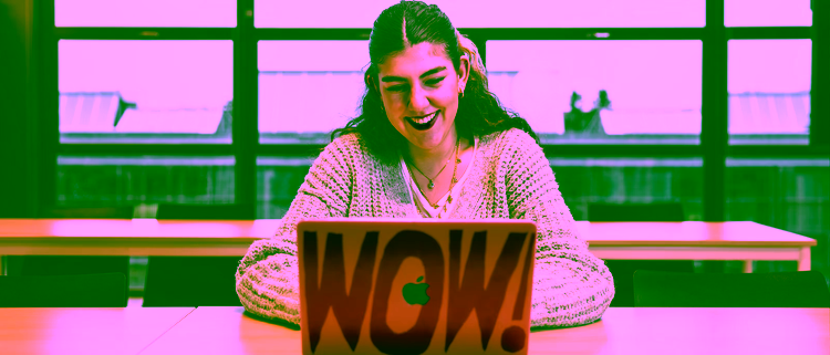 A bright workspace where a woman smiles to her laptop