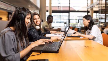 Students sitting at the table with their laptops open
