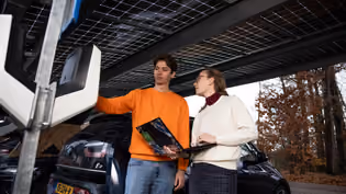 Inspection under solar carport with EV, showcasing integration of renewable energy and smart mobility solutions.