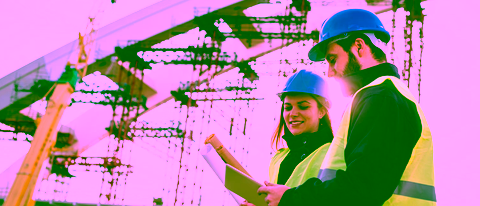 Two engineers with construction drawings at a bridge under construction