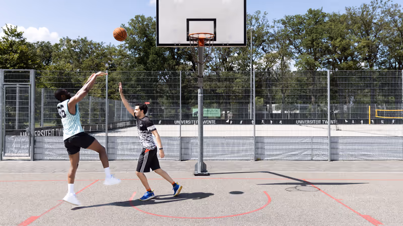 Two students playing basketball on campus.