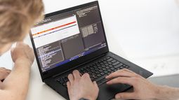 Two Computer Science students work on a laptop displaying code and data analysis.