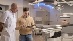 Health Sciences student discusses the use of surgical equipment with a doctor in the operating room.