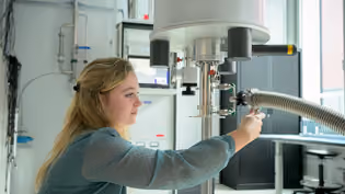 Student is adjusting a setup and taking measurements in a laboratory for quantum research.