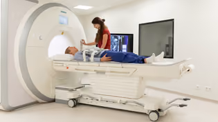 Student operates an MRI scanner while a patient lies on the table, ready for a scan.