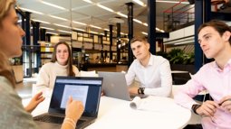 students at round table looking at one for presentation