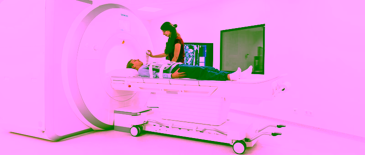 Student operates an MRI scanner while a patient lies on the table, ready for a scan.
