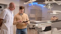 Health Sciences student discusses the use of surgical equipment with a doctor in the operating room.