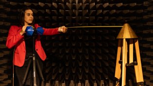 An Electrical Engineering student stands in an anechoic chamber, testing her project work.