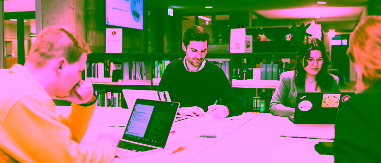 Students Public Administration studying together in a university library with laptops and books