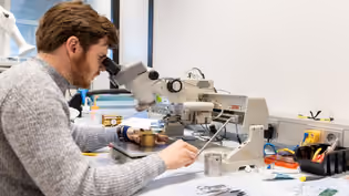 Electrical Engineering student works with a microscope and electronic components on a  lab workbench.