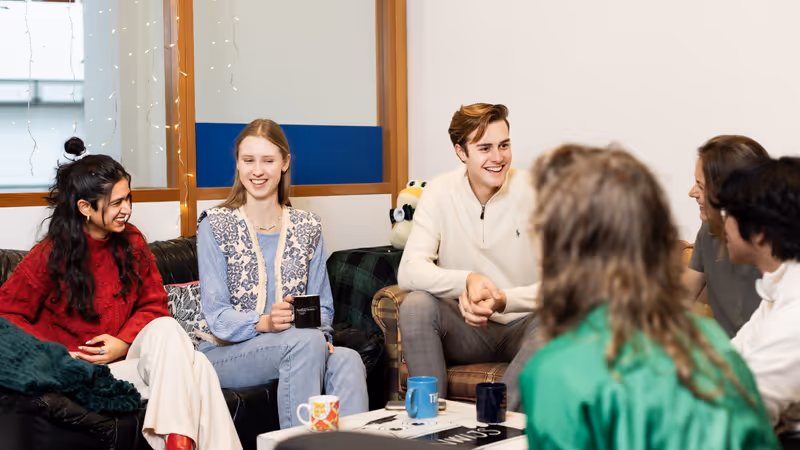 A group of six students sitting in a study association room talking.
